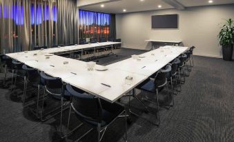 a conference room with a long table , chairs , and a large window depicting a cityscape at Mercure Warragul