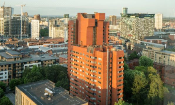 a tall red brick building is situated in the center of a city , surrounded by other buildings and trees at Hampton by Hilton Birmingham Broad Street