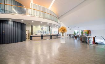 a modern hotel lobby with a curved ceiling , large windows , and a reception desk with a vase of flowers at Duja Bodrum