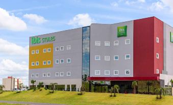 "a modern building with a red and yellow facade , green letters , and a green sign that reads "" ibis styles .""." at Ibis Styles Birigui