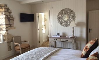 a cozy bedroom with a white bed , a chair , and a tv mounted on the wall at King William Inn