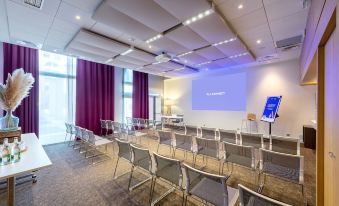 a conference room with chairs arranged in rows and a large screen on the wall at Novotel Toulouse Centre Compans Caffarelli
