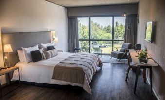 a modern bedroom with a king - sized bed , wooden floors , and a large window overlooking the outdoors at Kos Pilar Hotel