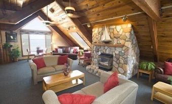 a cozy living room with a fireplace and stone walls , featuring two couches , a coffee table , and a dining table at Pinestead Reef Resort