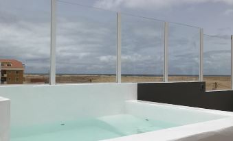 a rooftop pool surrounded by a white building , with a view of the ocean in the background at Blue Eagle Guesthouse