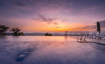 a serene scene of a swimming pool with a staircase leading into the water , set against a backdrop of a beautiful sunset at Coorg Cliffs Resort
