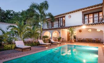a large white house with a swimming pool in the backyard , surrounded by palm trees at San Rafael