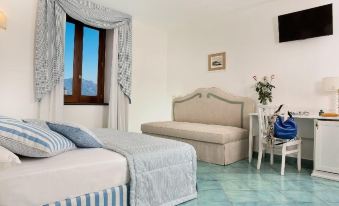 a bedroom with a large window , blue and white striped bed , and a couch in the corner at Villa Maria