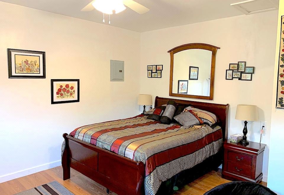 a cozy bedroom with a wooden bed , a ceiling fan , and various pictures on the wall at Micosta Leisure Inn