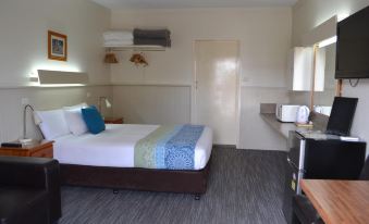 a modern hotel room with a bed , desk , and kitchenette , along with a small refrigerator and microwave at Gatton Motel