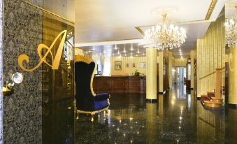 a luxurious hotel lobby with a blue and black chair in the center , surrounded by gold accents and a chandelier at Hotel Alexandra