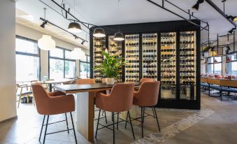 a modern restaurant with a dining table and chairs , as well as a wine cellar filled with bottles at ibis Lyon Sud Oullins