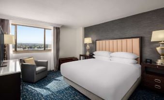 a large bed with white linens is in a room with blue carpeting and a window at Hilton Concord