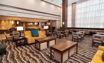 a spacious hotel lobby with various seating options , including couches , chairs , and tables , as well as a bar area at Staybridge Suites Washington DC East - Largo