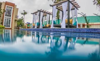 a large outdoor swimming pool surrounded by lush greenery , with several lounge chairs placed around the pool area at Mayas