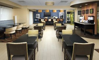 a spacious , well - lit restaurant with several tables and chairs , a bar area , and large windows at Hampton Inn Lenoir City