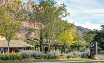 a building with a sign in front of it , surrounded by trees and mountains in the background at Desert Pearl Inn