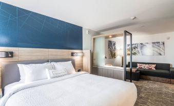 a large bed with white sheets is in a room with a blue accent wall and a door leading to another room at SpringHill Suites Oklahoma City Downtown/Bricktown