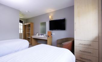 a modern hotel room with a large flat - screen tv , comfortable beds , and a desk area at The Woolpack Inn