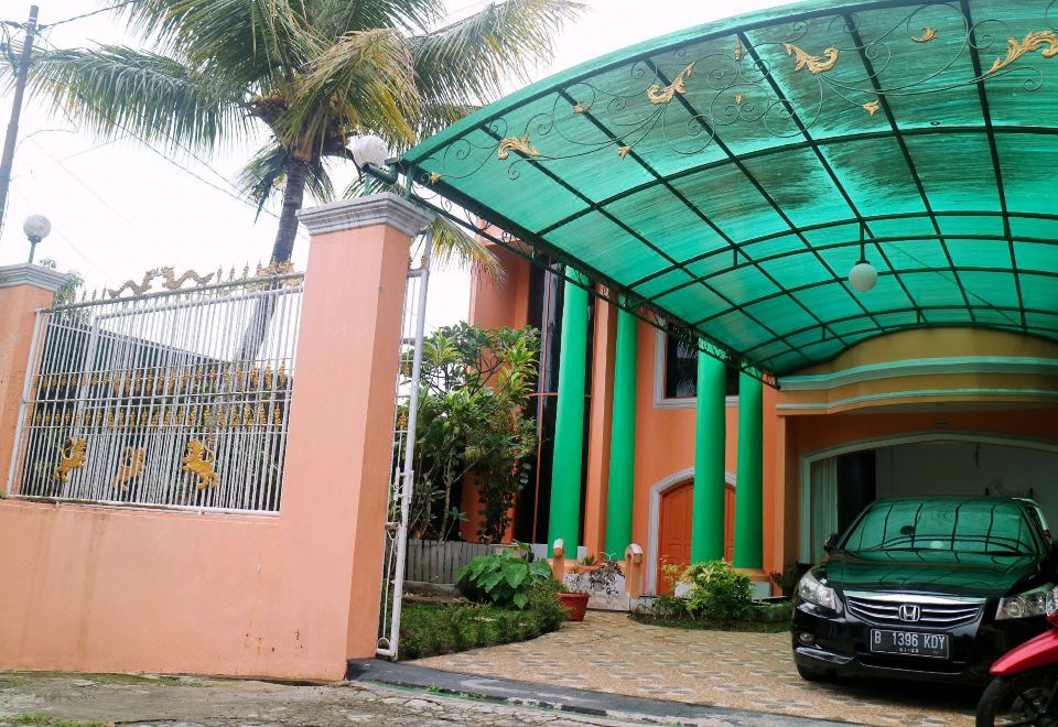 a house with a green roof and a car parked in front of it , surrounded by palm trees at Mason Residence Syariah Ciawi