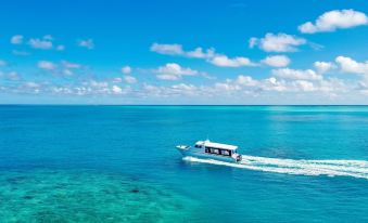 a boat is sailing in the ocean with clear blue water and a few clouds in the sky at Kagi Maldives Resort & Spa