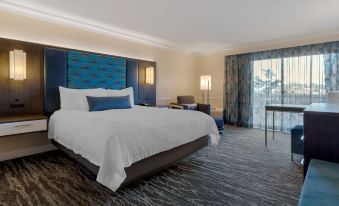 a large bed with white sheets and a blue headboard is in a room with a window at Best Western Plus Novato Oaks Inn