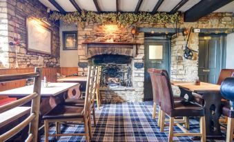 a cozy restaurant interior with a fireplace , wooden beams on the ceiling , and blue and white plaid carpeting at Thames Head Inn
