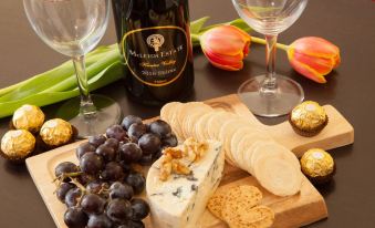 a wooden cutting board filled with various types of cheese , grapes , and crackers next to a bottle of wine at Wine Country Motor Inn