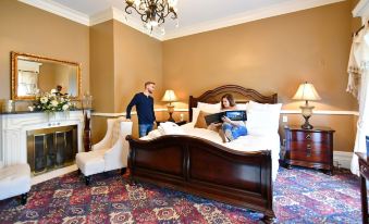 a man and a woman are standing in a bedroom , reading a book on the bed at Avon Inn