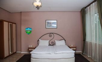 a large bed with white linens is situated in a room with pink walls and a hanging light fixture at Holiday Village