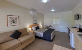 a hotel room with a bed , couch , and dining table , all neatly arranged in a clean and well - organized setting at Country Roads Motor Inn