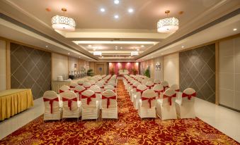 a large conference room with rows of chairs and red carpet , decorated with gold and white chandeliers at Freesia by Express Inn