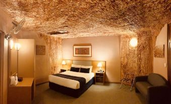 a modern hotel room with wooden ceiling , white walls , and a bed , along with other amenities such as a couch , nightstand , and at Desert Cave Hotel