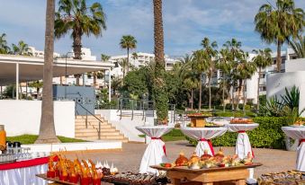 a buffet table with various food items , including pastries and fruits , is set up in a courtyard at Allegro Agadir