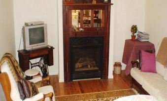a cozy living room with hardwood floors , a fireplace , and a television mounted on the wall at Albury Cottages