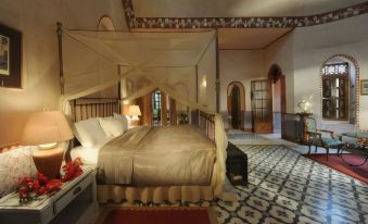 a large bed with a canopy is in the middle of a room with patterned flooring at Al Moudira Hotel