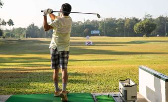 a man is practicing his golf swing on a driving range , swinging a golf club at Camino Real Hotel