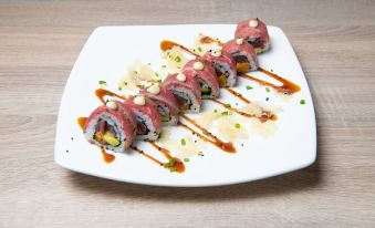 a plate of sushi on a white plate , topped with sauce and garnished with green onions at Kunuku Resort All Inclusive Curacao, Trademark by Wyndham