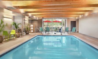 a large swimming pool with a wooden ceiling and lounge chairs is surrounded by potted plants at Home2 Suites by Hilton Harrisburg North