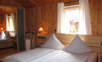 a cozy wooden cabin bedroom with a large bed , two nightstands , and a window with curtains at Martin