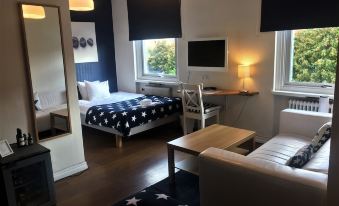 a small , cozy living room with a couch , a bed , and a tv . also a dining table in the room at Port Hotel