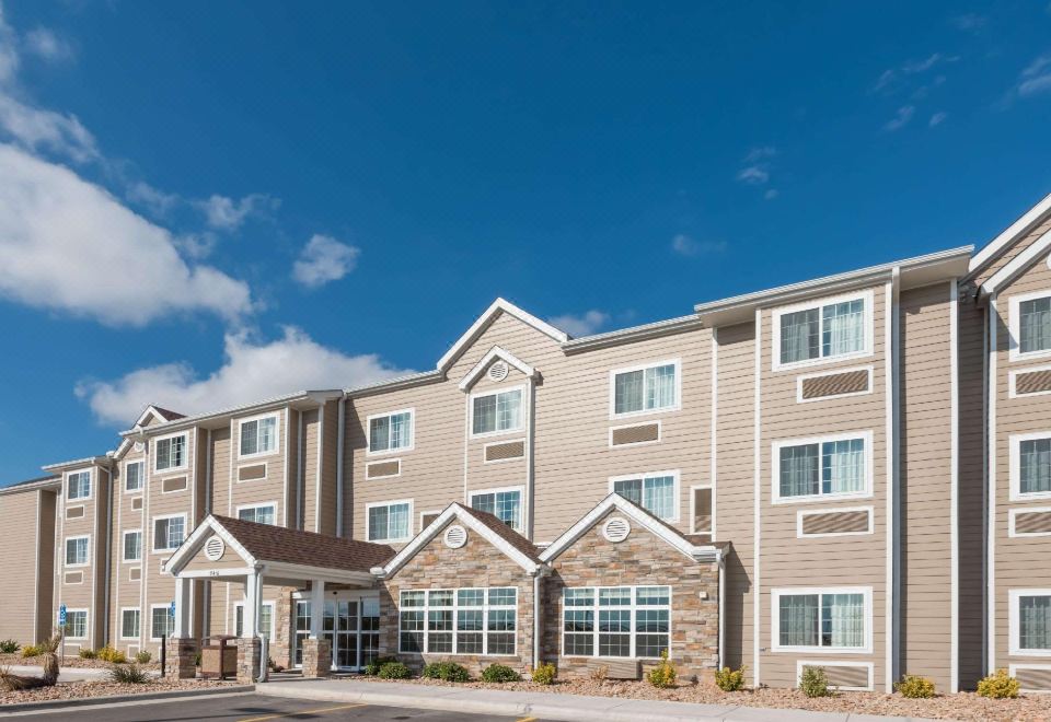 an exterior view of a hotel building with multiple floors , surrounded by trees and other buildings at Microtel Inn & Suites by Wyndham Sweetwater