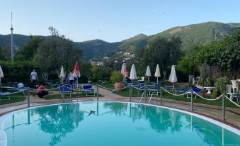 a large outdoor swimming pool surrounded by lounge chairs and umbrellas , with a mountain in the background at Rabbit