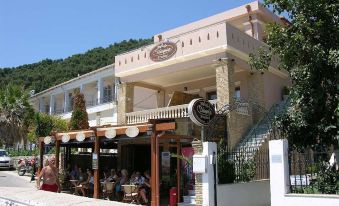 "a white building with a sign that says "" coffee and pastries "" is surrounded by trees , with people sitting outside" at Utopia