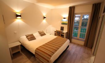 a large bed with white sheets and a striped blanket is in a room with wooden floors at Le Continental