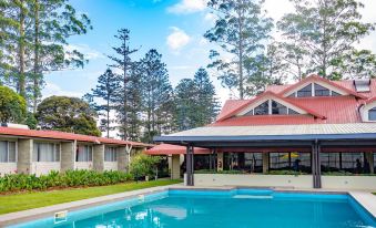 a large house with a swimming pool and red roof is surrounded by trees and grass at Highlander Hotel