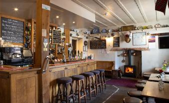 a cozy pub with wooden benches , stools , and a fireplace , inviting customers to enjoy their drinks at The Durant Arms