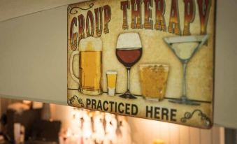 a sign for a group therapy bar with various alcoholic beverages , such as beer and wine , displayed on the wall at The Chequers Inn