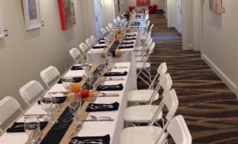 a long dining table with white chairs and black and white tablecloths is set up in a hallway at The Mantissa Hotel