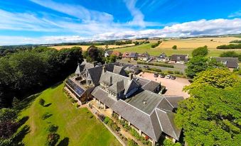 aerial view of a large house surrounded by green fields and trees , with a blue sky overhead at Old Manor Hotel